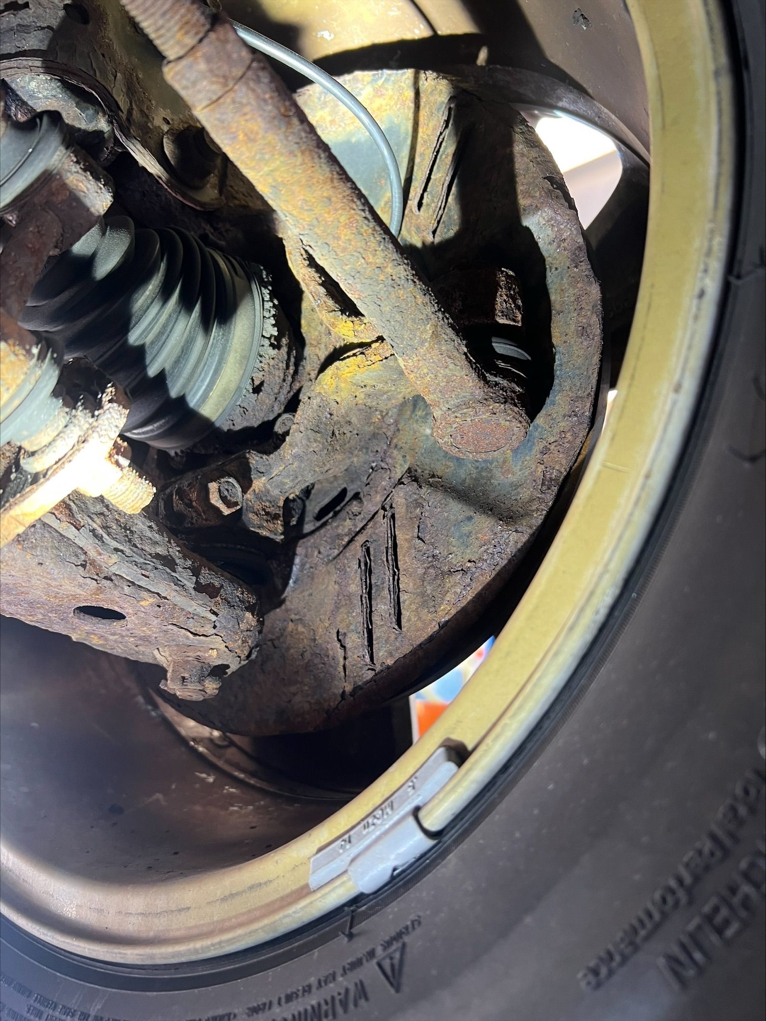 Close-up of a car wheel hub and suspension with a brake rotor and dirty metal components.