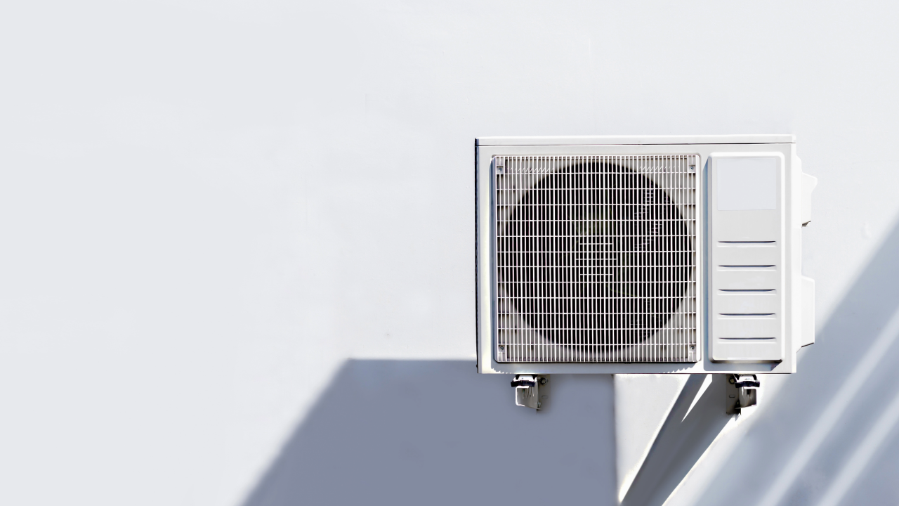 A white air conditioner is mounted on a white wall.