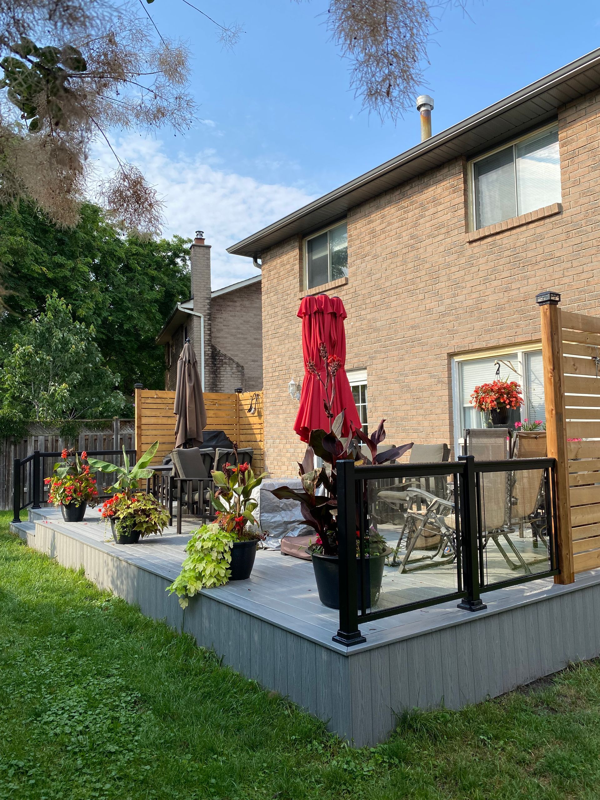A backyard with a patio , chairs , umbrellas and potted plants.