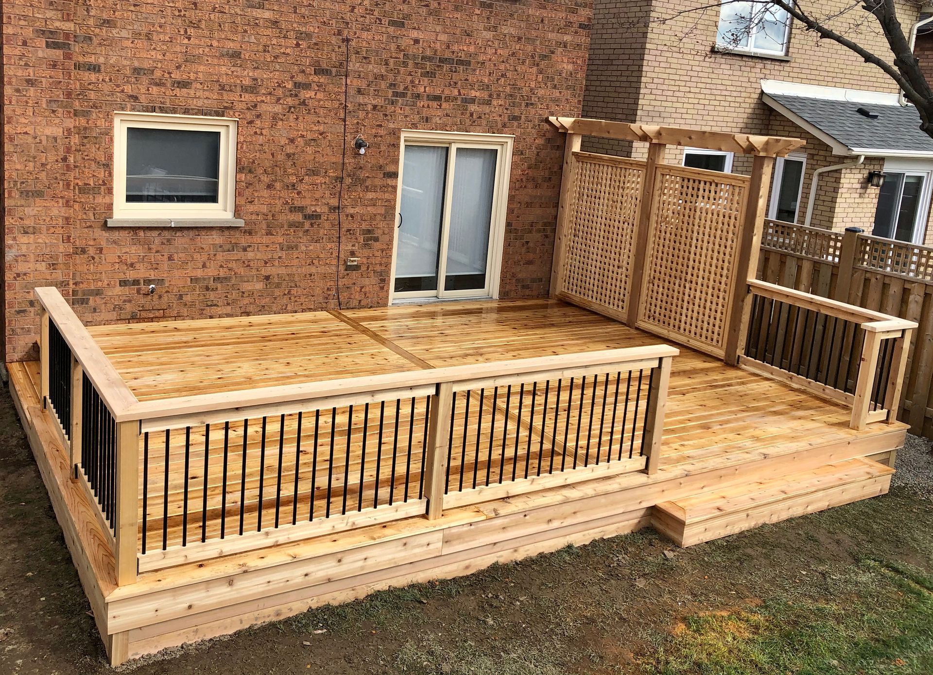A wooden deck is sitting in front of a brick house.