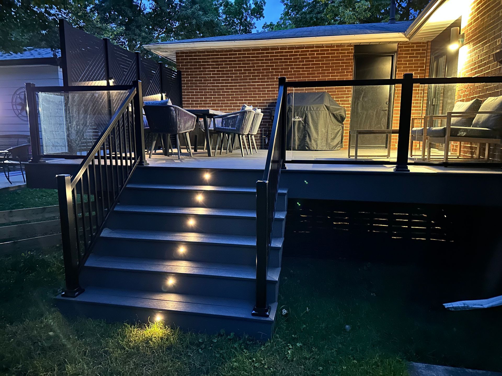 A deck with stairs leading up to it is lit up at night.