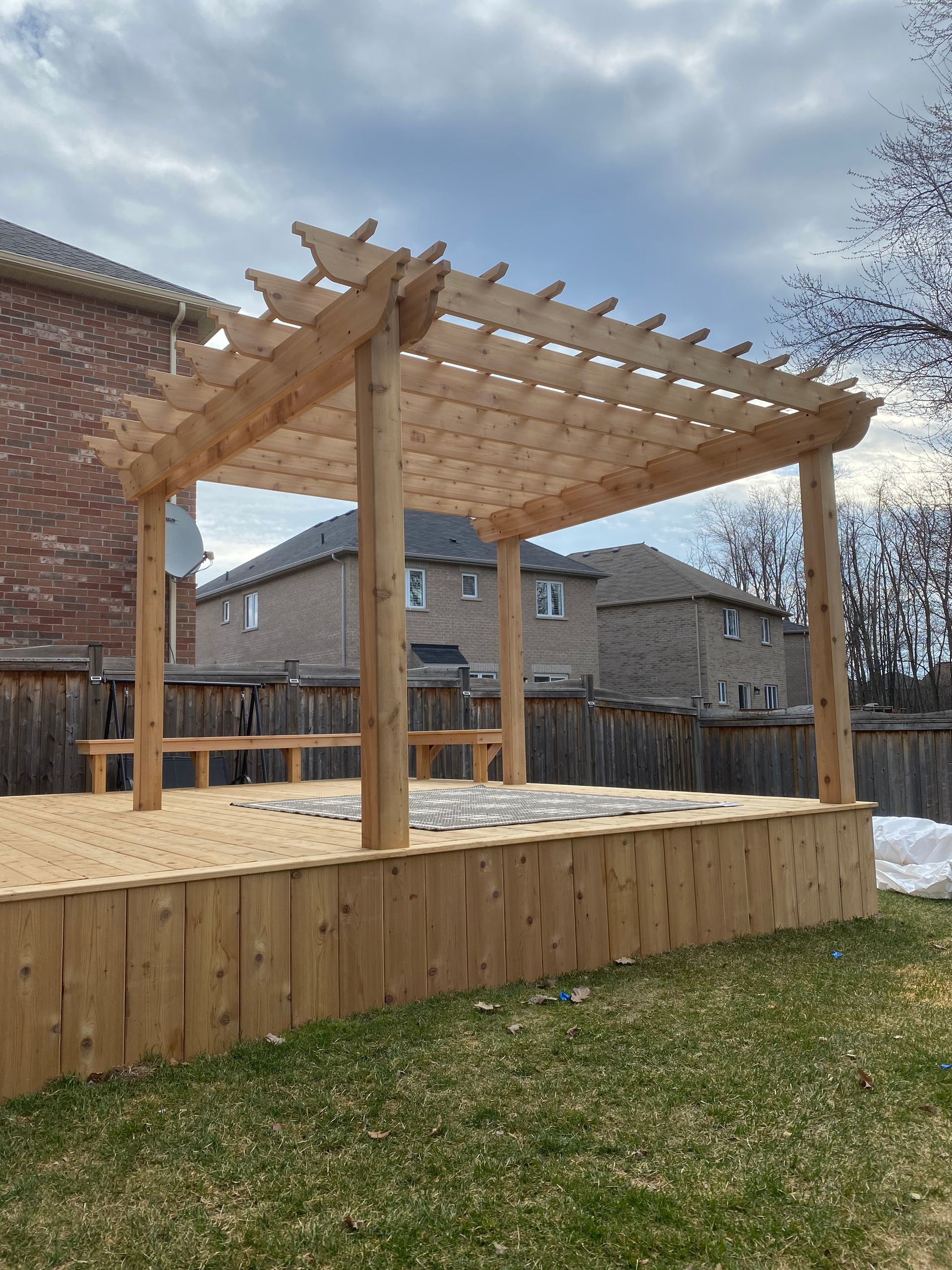 A wooden pergola is sitting on top of a wooden deck.