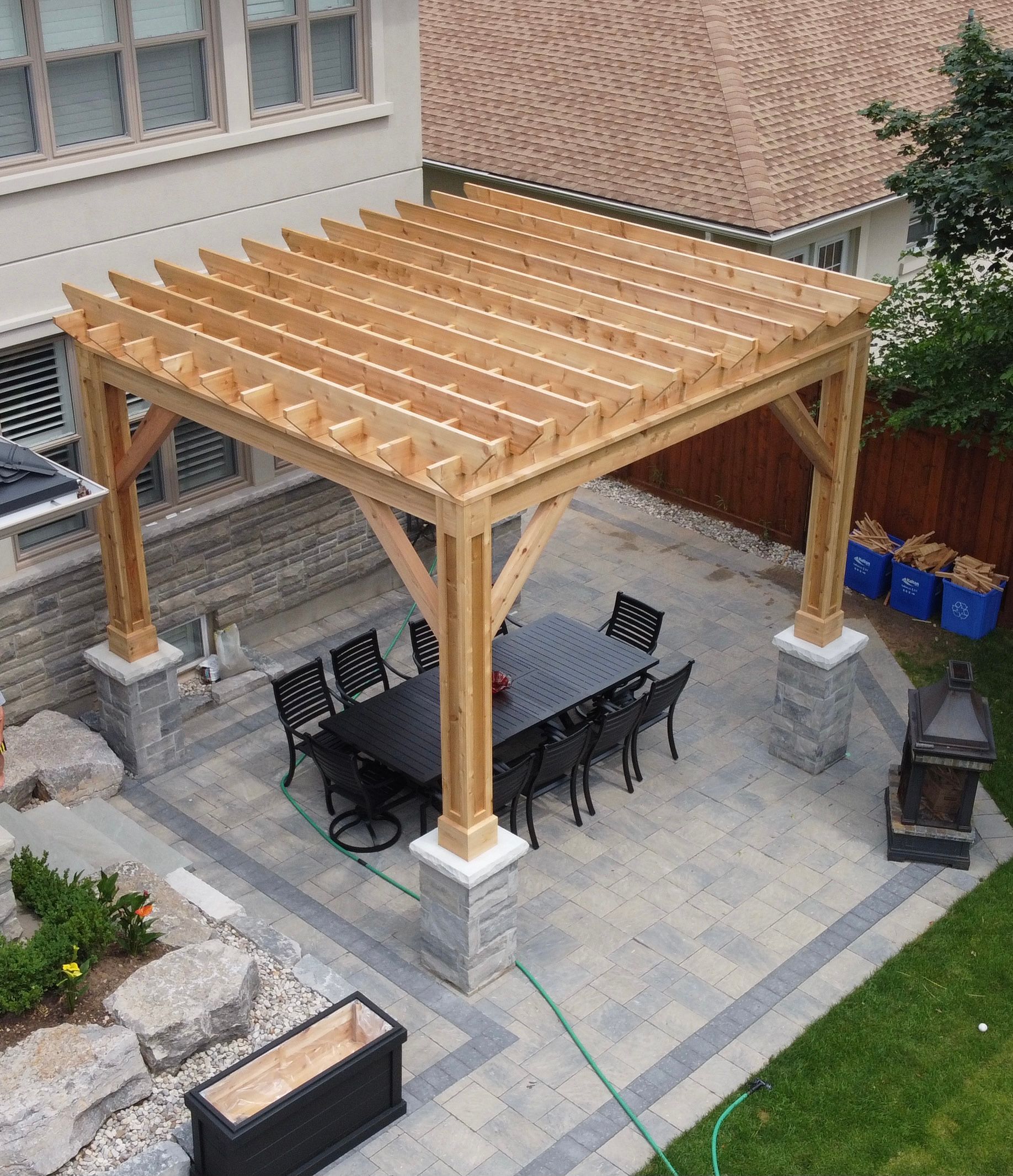 An aerial view of a wooden pergola with a table and chairs underneath it.