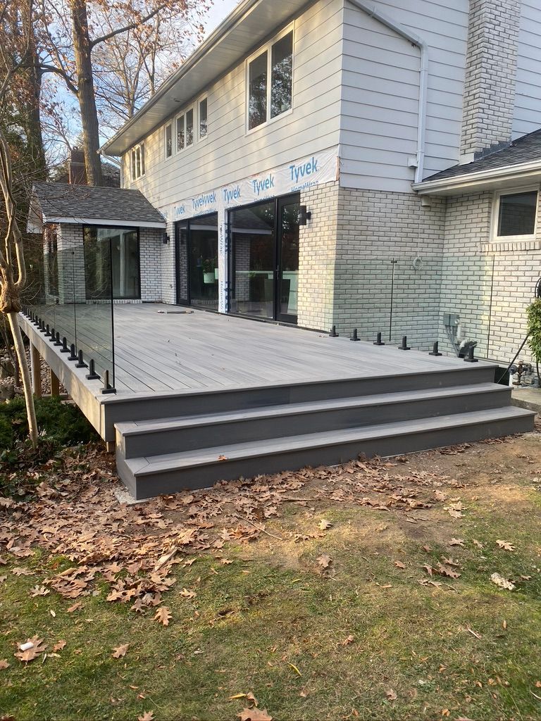 Backyard deck with wide steps and a covered patio beside a two-story house