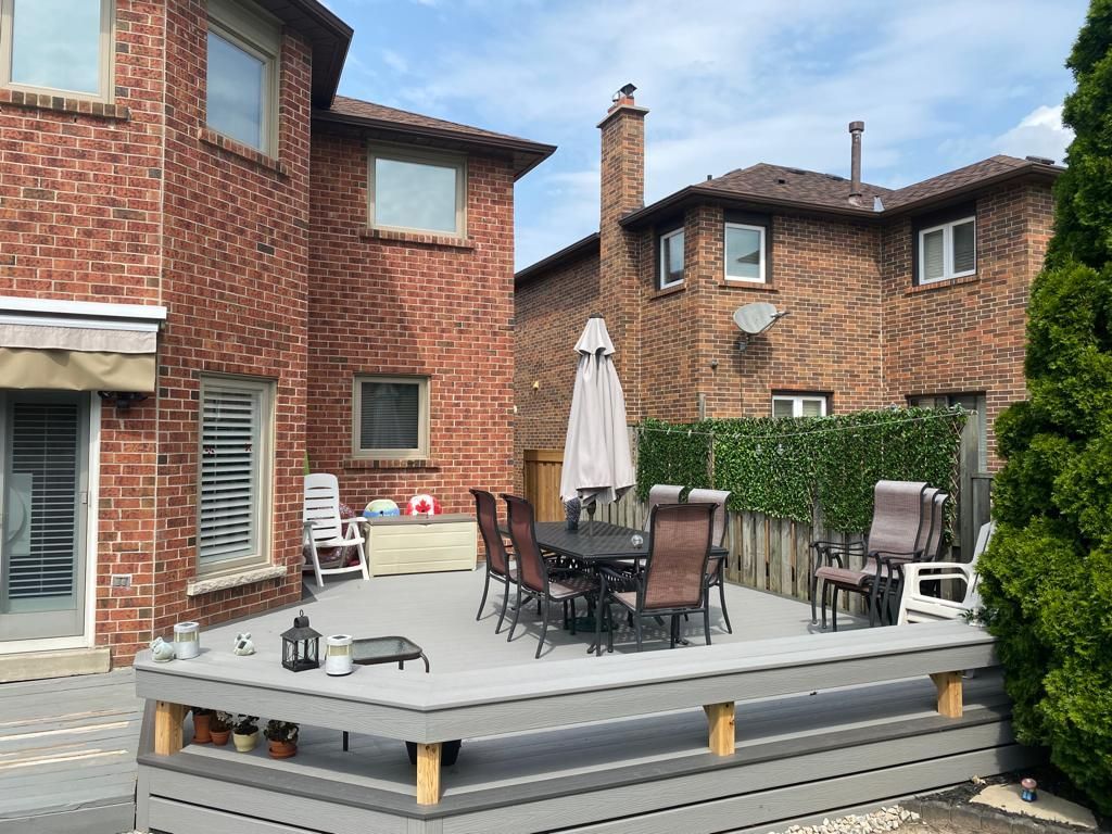 A patio with a table and chairs and an umbrella in front of a brick house.