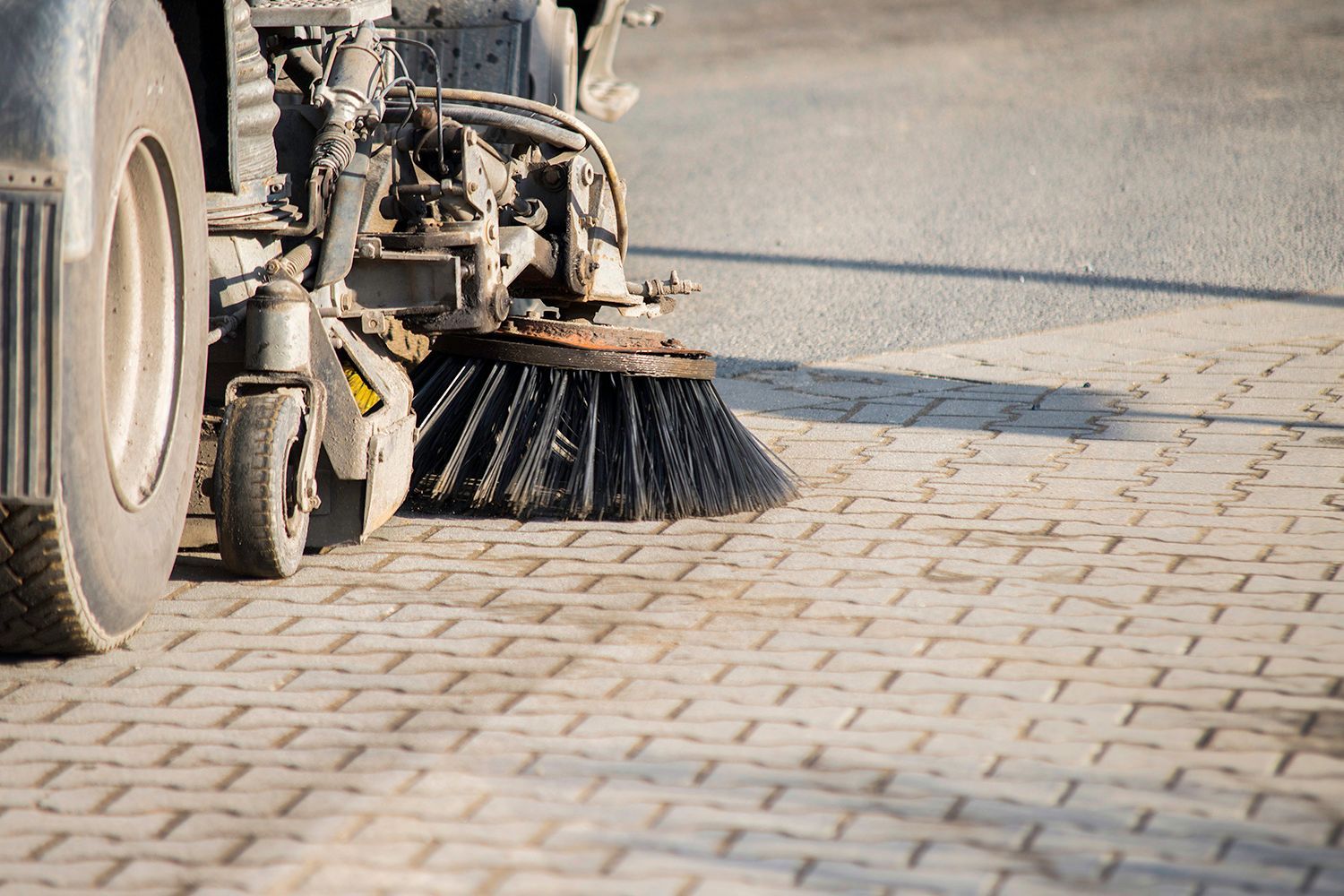 Street sweeper's brush sweeping a paved surface, detail shot.
