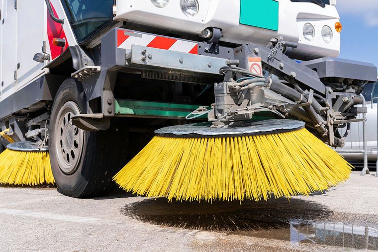 Street sweeper with yellow brushes cleaning a paved surface. Street sweeper with yellow brushes cleaning a paved surface.