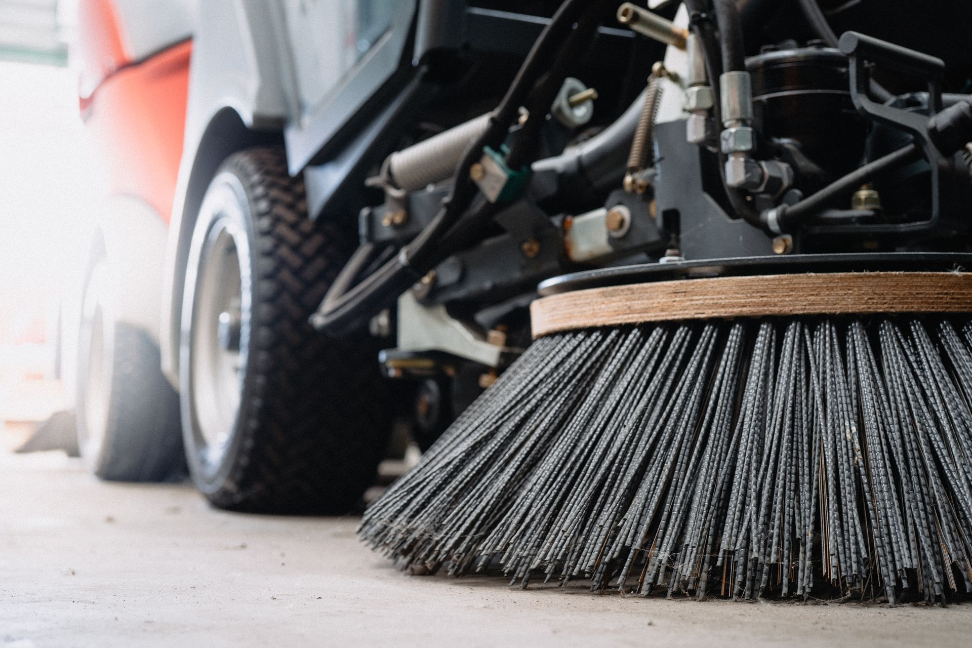 Close-up of street sweeper brush attachment cleaning pavement.