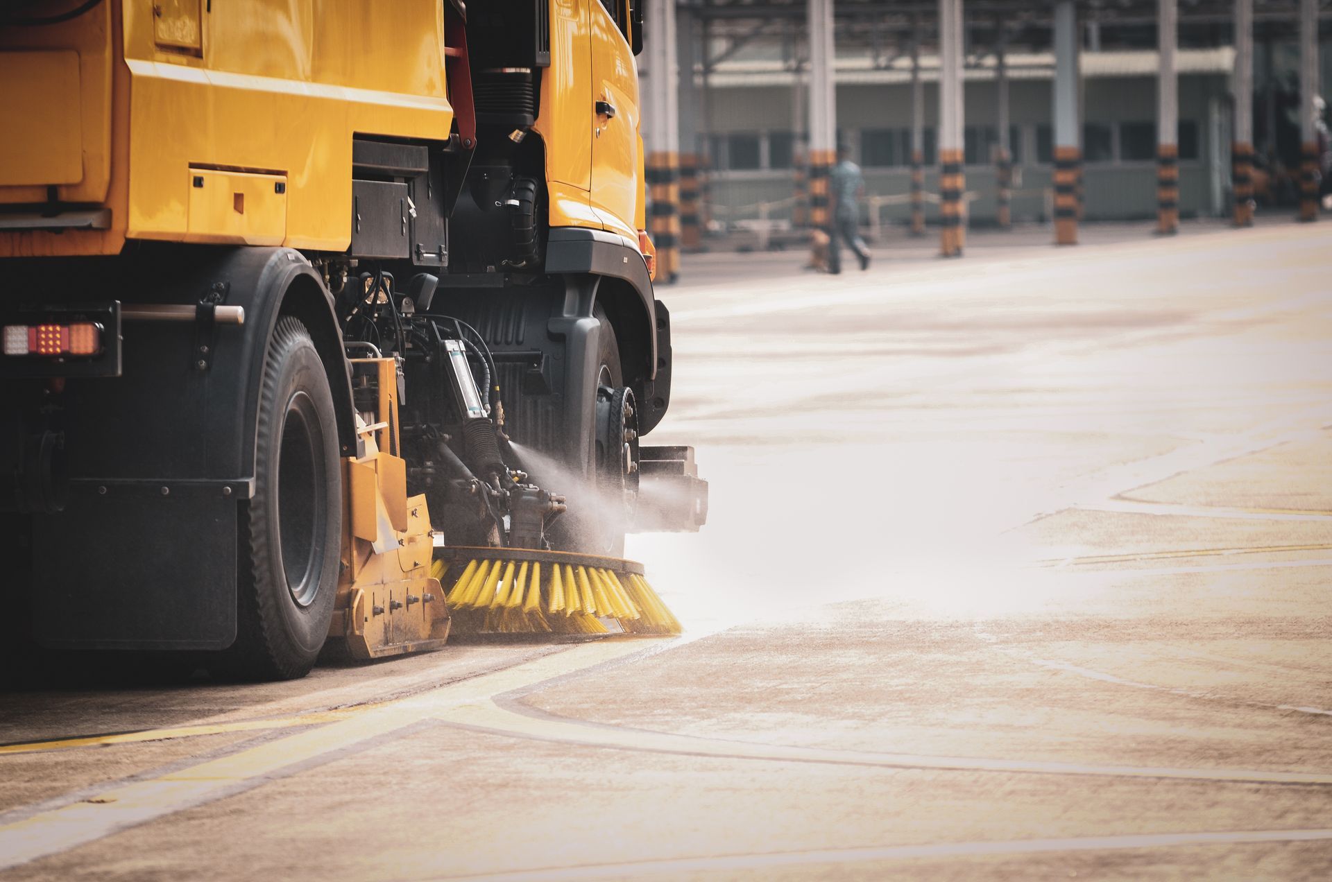 An industrial road sweeper machine actively cleaning.