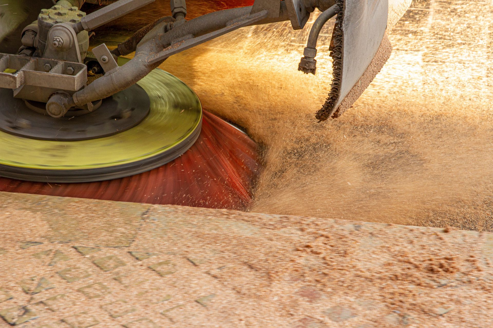 Sweeper brush clearing construction dust and debris from pavement