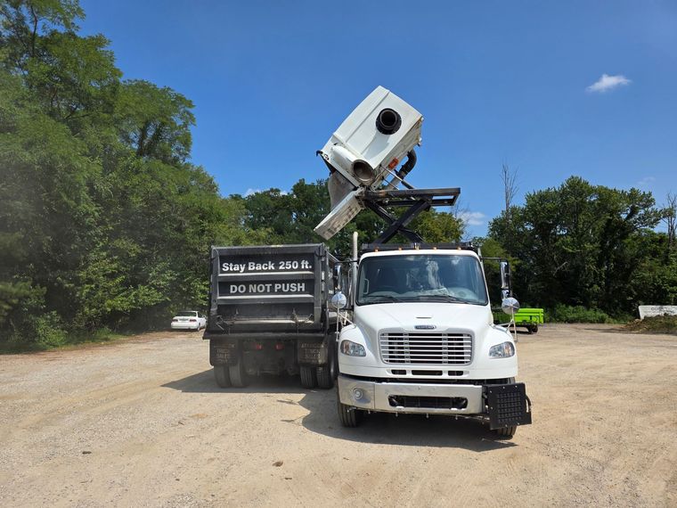 Street sweeper cleaning a brick-paved public park with benches and trees. White and dark gray vehicle. Street sweeper cleaning a brick-paved public park with benches and trees. White and dark gray vehicle.