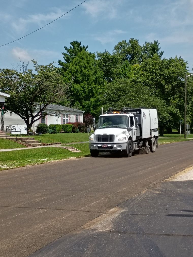 Street sweeper with blue brushes cleaning a paved road. Street sweeper with blue brushes cleaning a paved road.