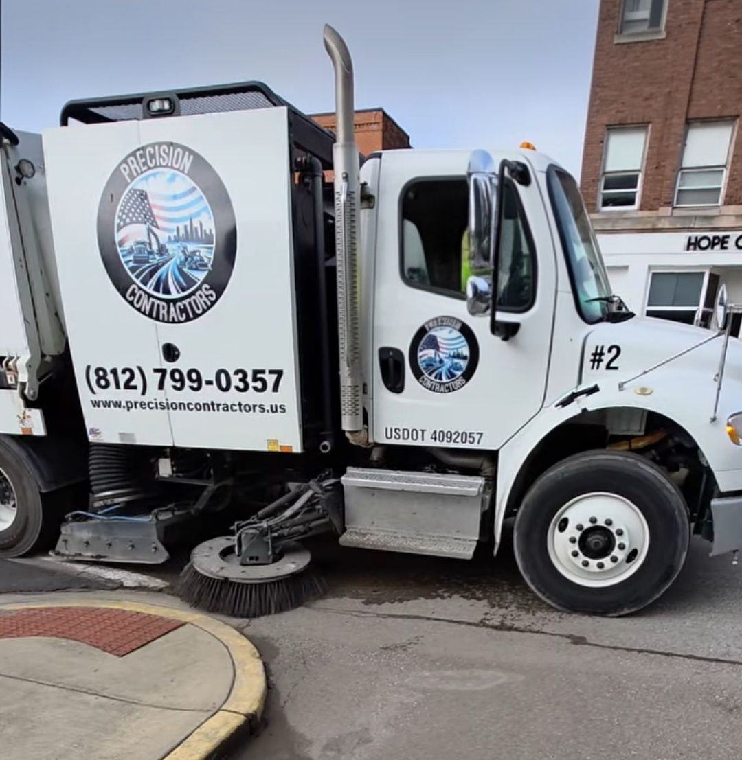 Man standing between two street sweepers, arms raised, in work clothes.