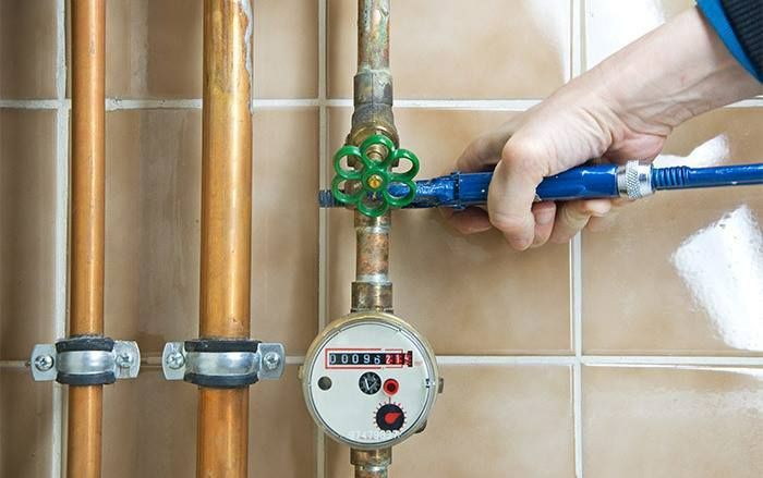 Hand turning a blue shutoff valve on a gas meter with copper pipes Hand turning a blue shutoff valve on a gas meter with copper pipes