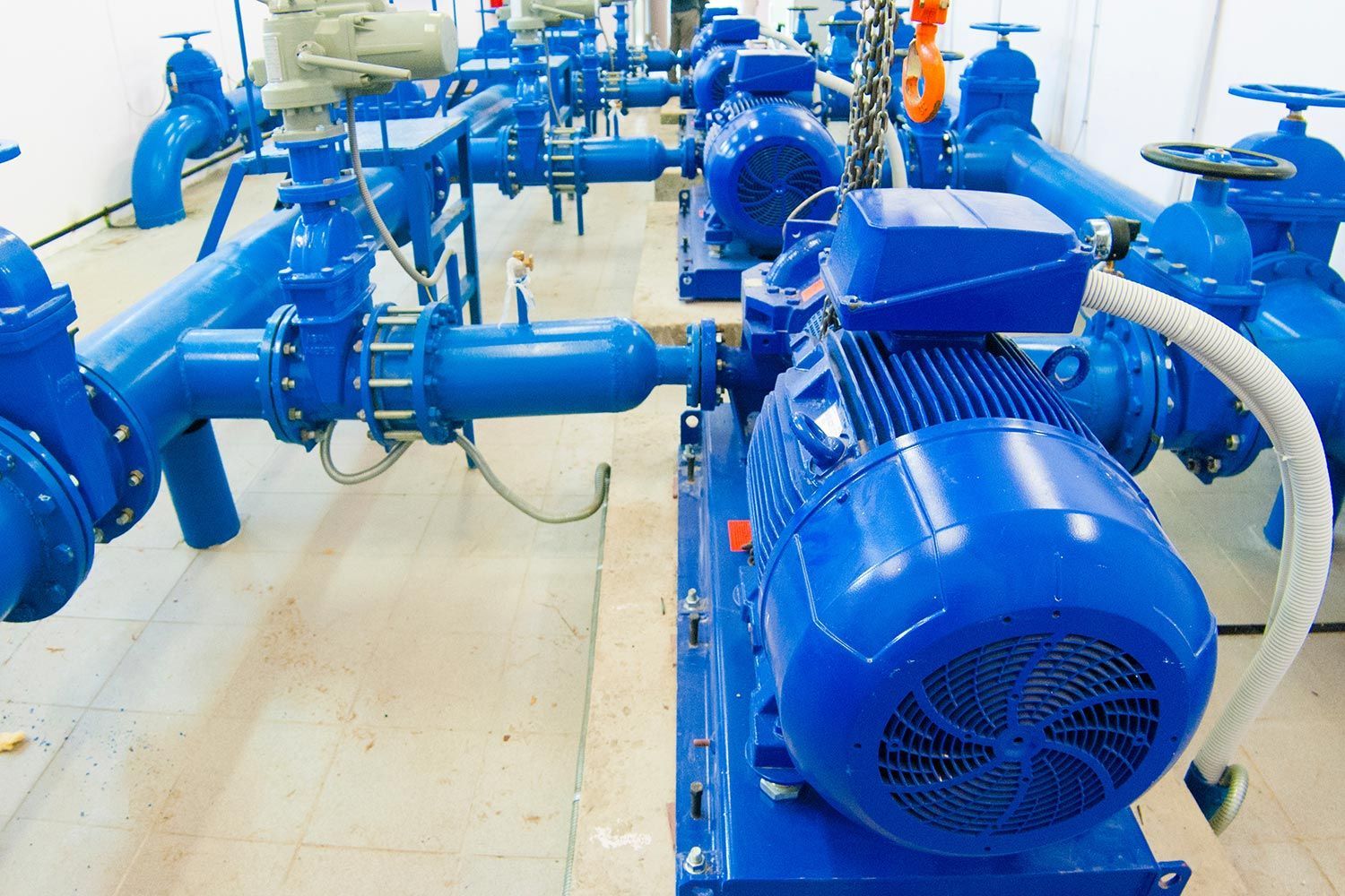 Blue industrial pumps and piping in a mechanical room Blue industrial pumps and piping in a mechanical room