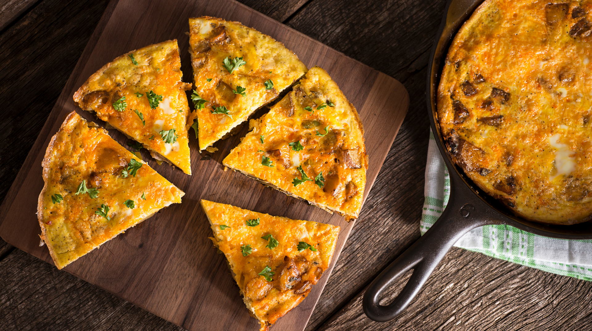 A pizza is sitting on a wooden cutting board next to a skillet.