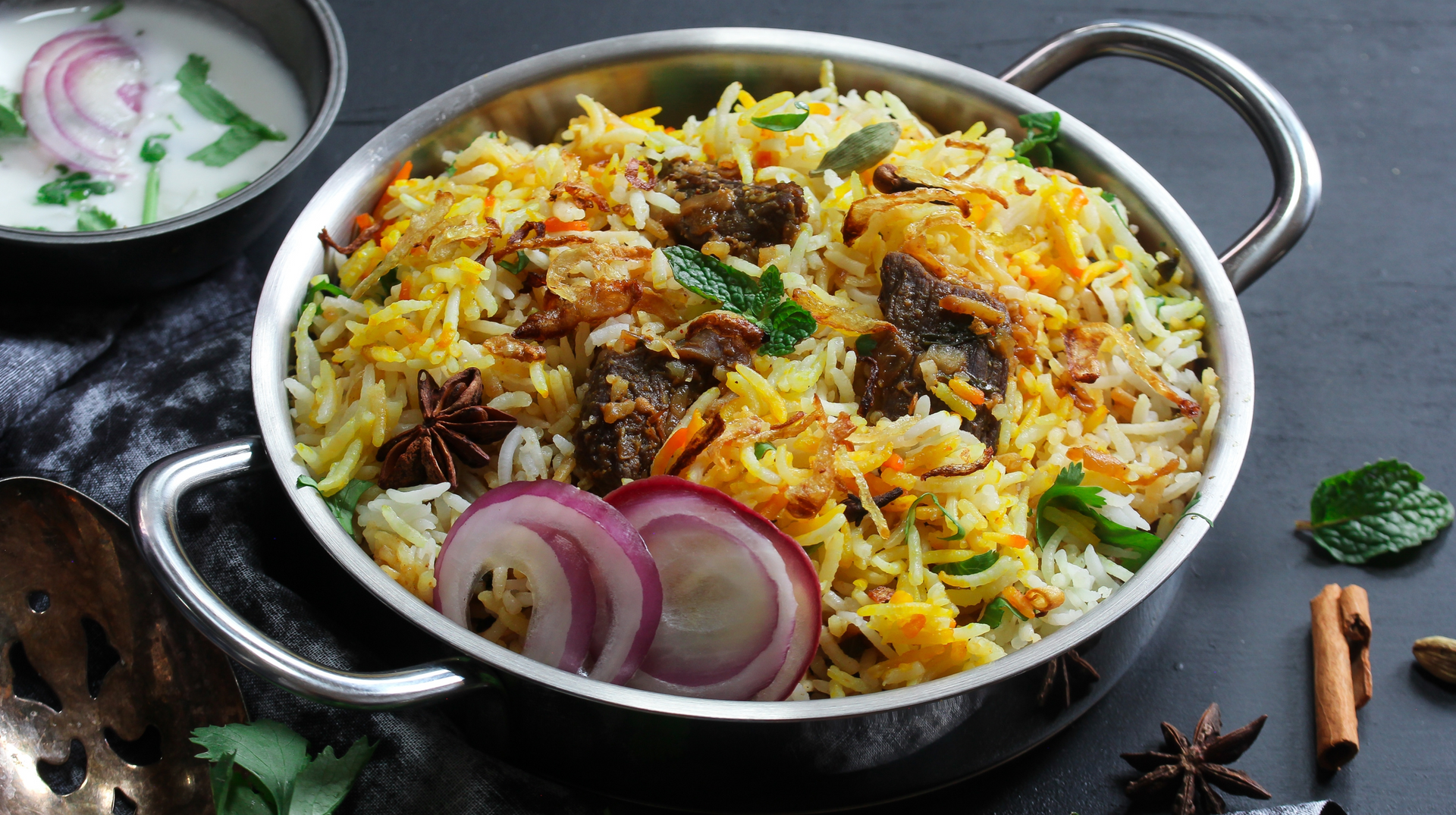 A pan filled with rice , meat and onions on a table.