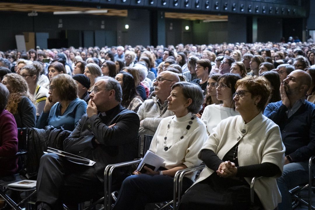 Un folto gruppo di persone è seduto in un grande auditorium.
