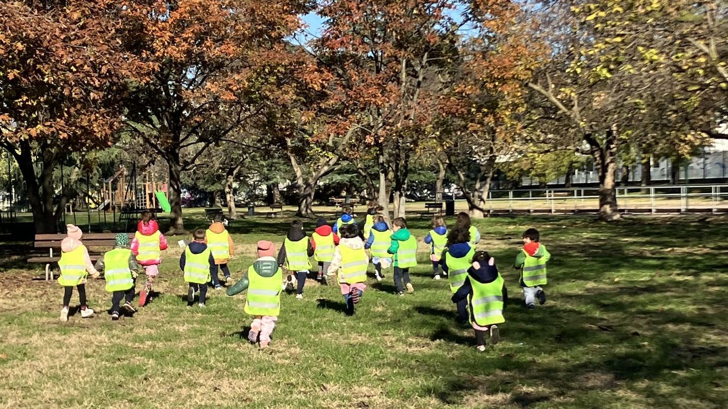 Un gruppo di bambini cammina tenendosi per mano lungo una strada acciottolata.