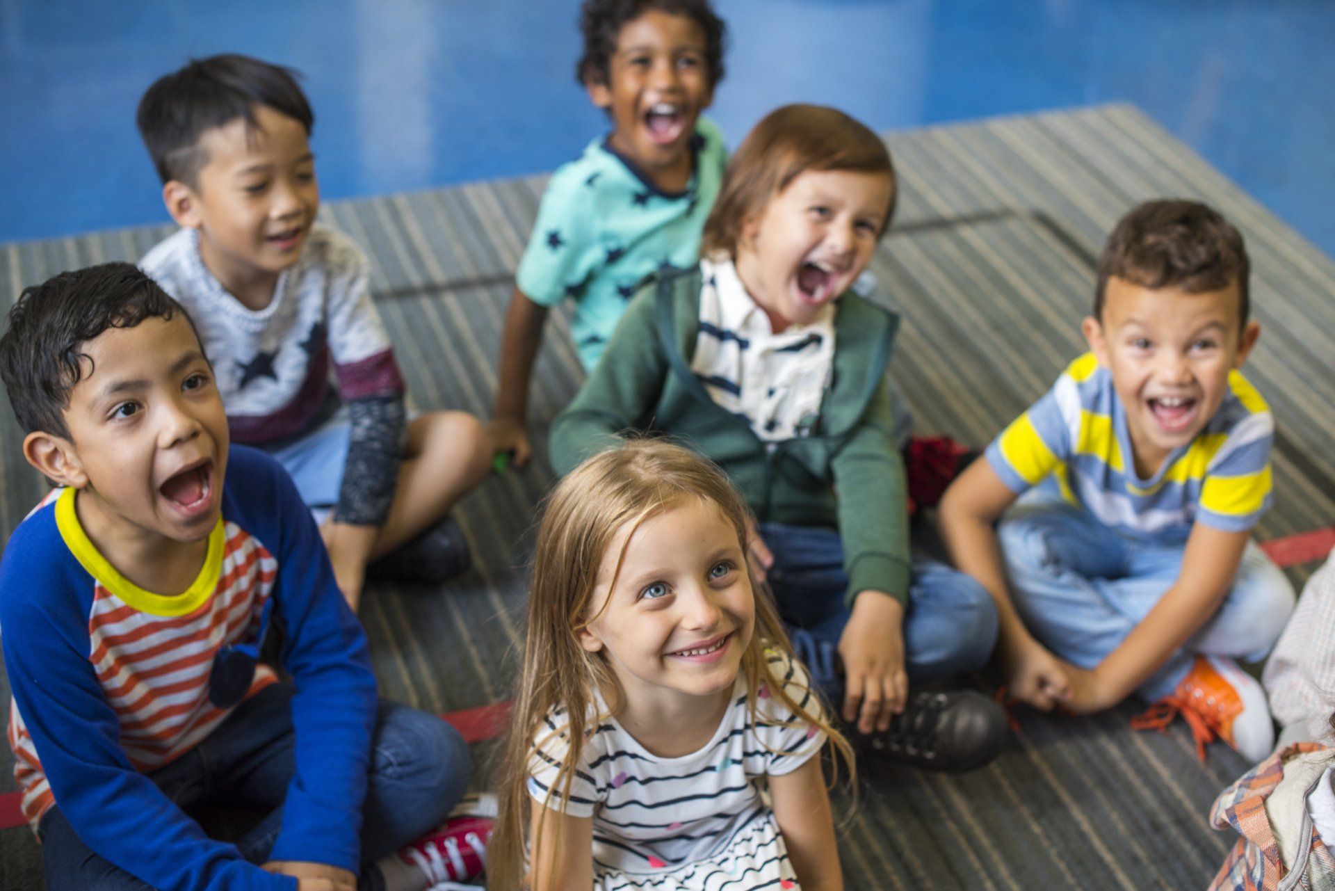 Un gruppo di bambini è seduto per terra in cerchio.