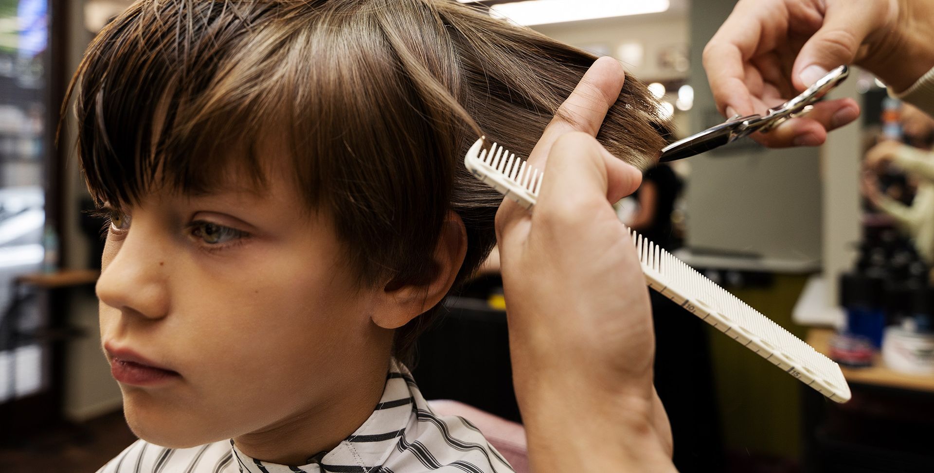 A man with a beard is getting his hair cut by a barber.