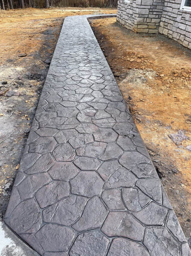 Worker measuring paving stones beside a tiled walkway with a tape measure and straightedge