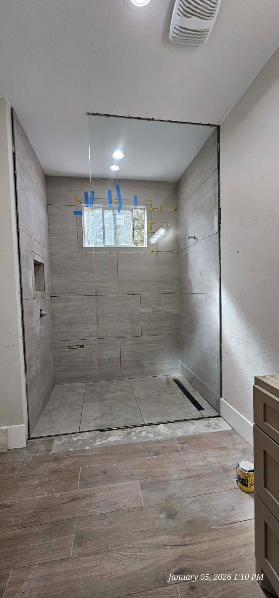 A walk-in shower with tiled walls and glass enclosure under construction in a bathroom.