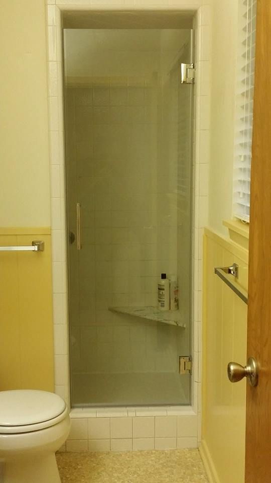Bathroom with a glass shower door, toilet, and yellow walls.