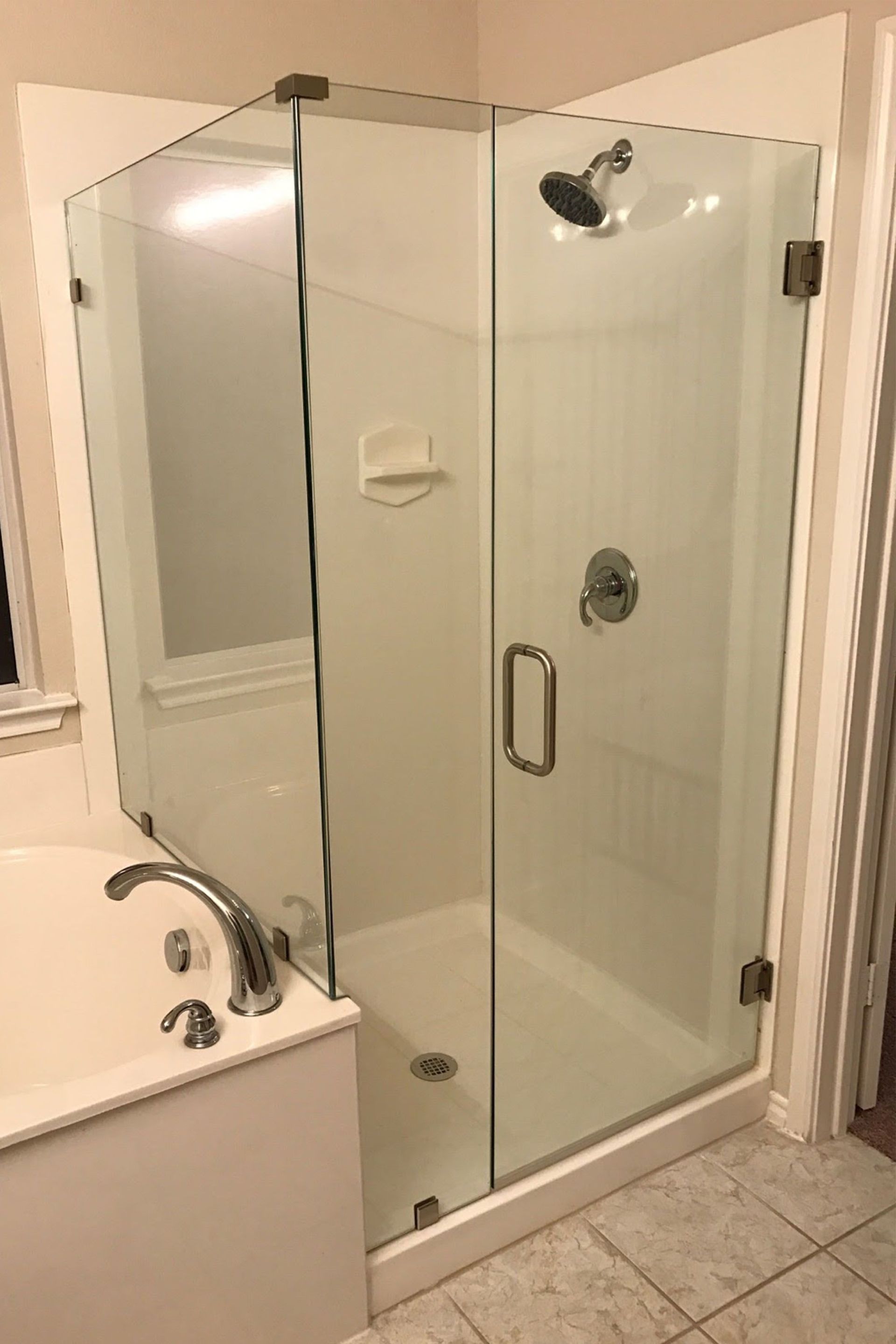 Glass shower enclosure in a bathroom with a showerhead and fixtures.