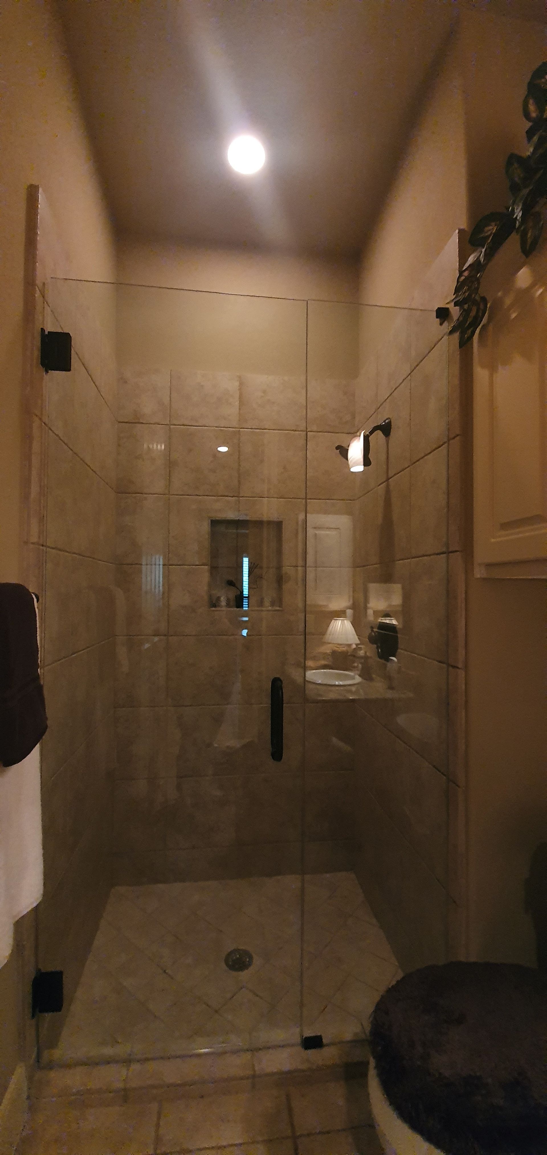 A walk-in shower with glass doors, tiled walls, and a recessed ceiling light.