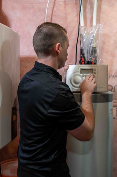 Man adjusts settings on a water softener unit in a basement.