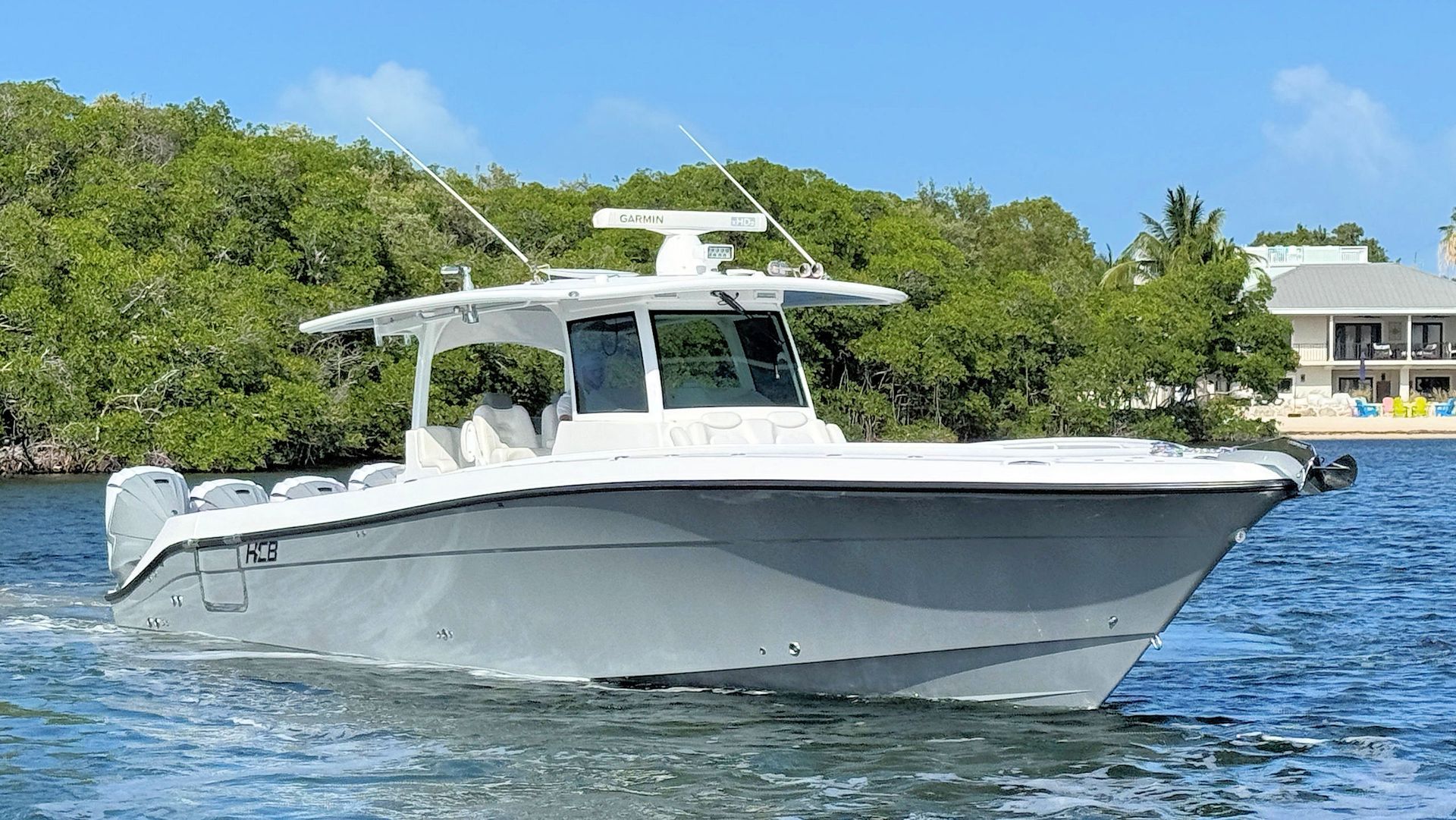 Center console fishing boat cruising on blue water near a tropical shoreline