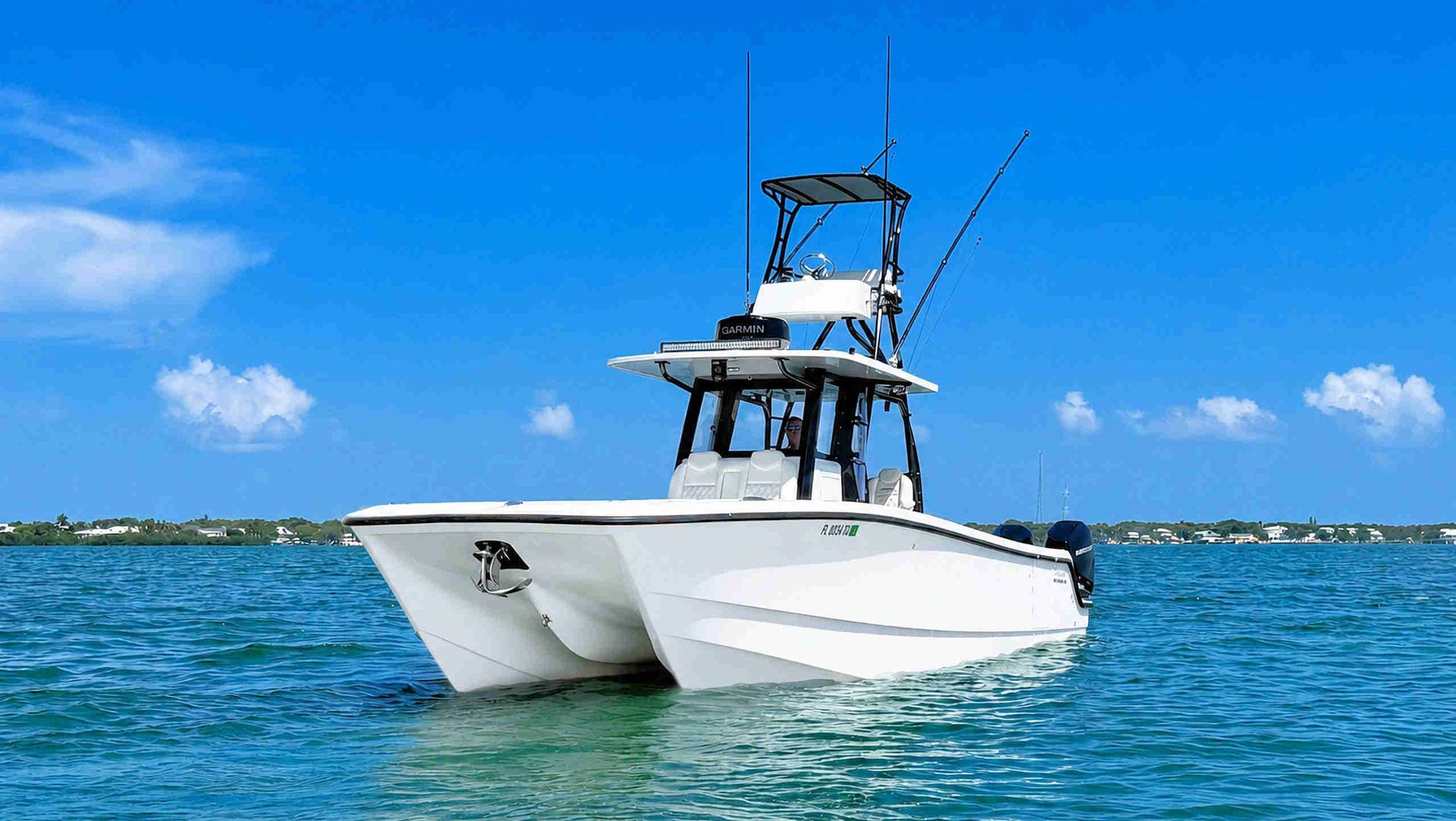 White catamaran center console fishing boat on blue water under a clear sky