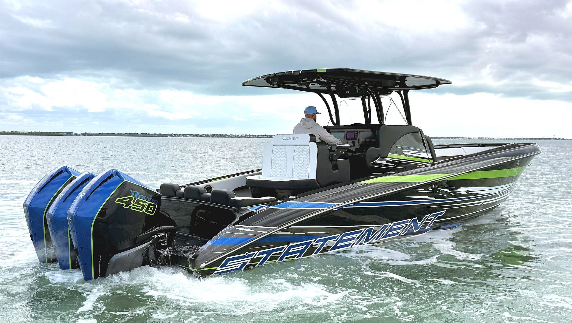 A sleek, patterned center-console boat with three blue outboard motors cruising on open water under a cloudy sky.