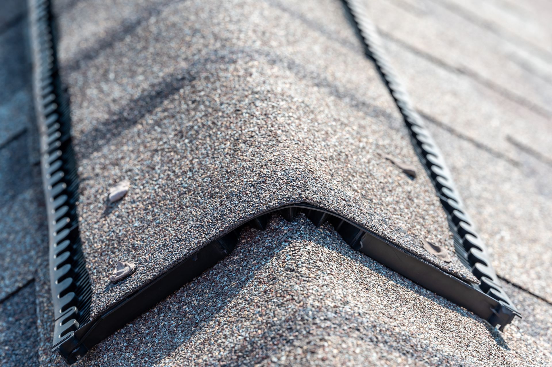 Close-up of a shingled roof with a damaged ridge vent