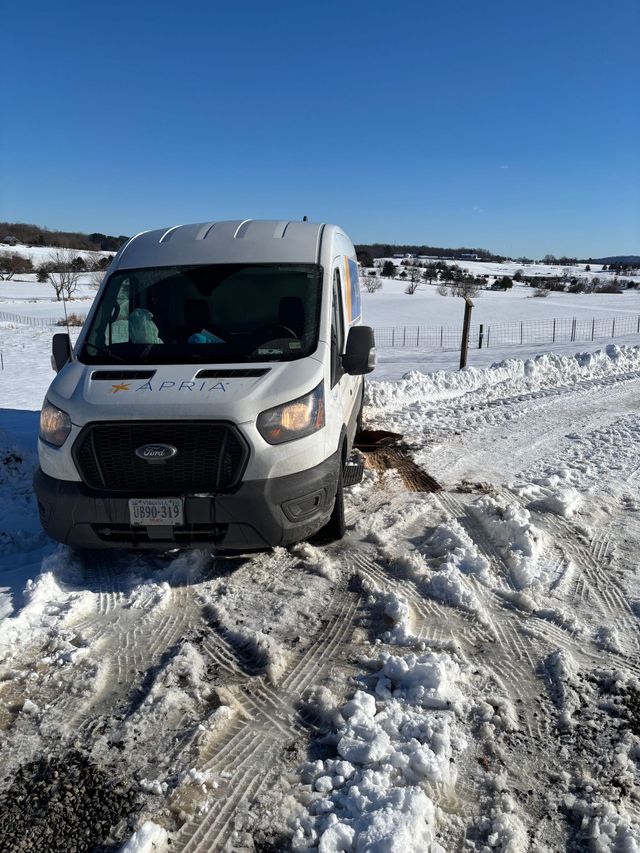 A white van is stuck in the snow on a snowy road.