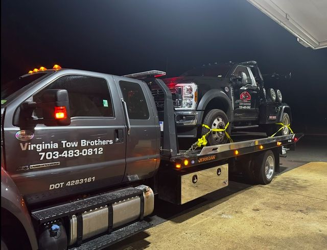 A tow truck is carrying two trucks on the back of it.
