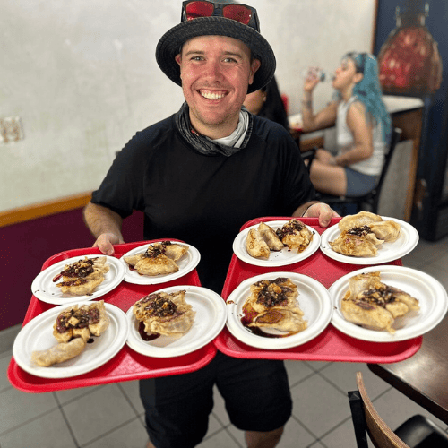Tour guide Ryan holding dumplings from Tasty Dumpling in Chinatown, NYC