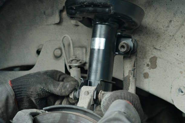 A person is fixing a shock absorber on a car.