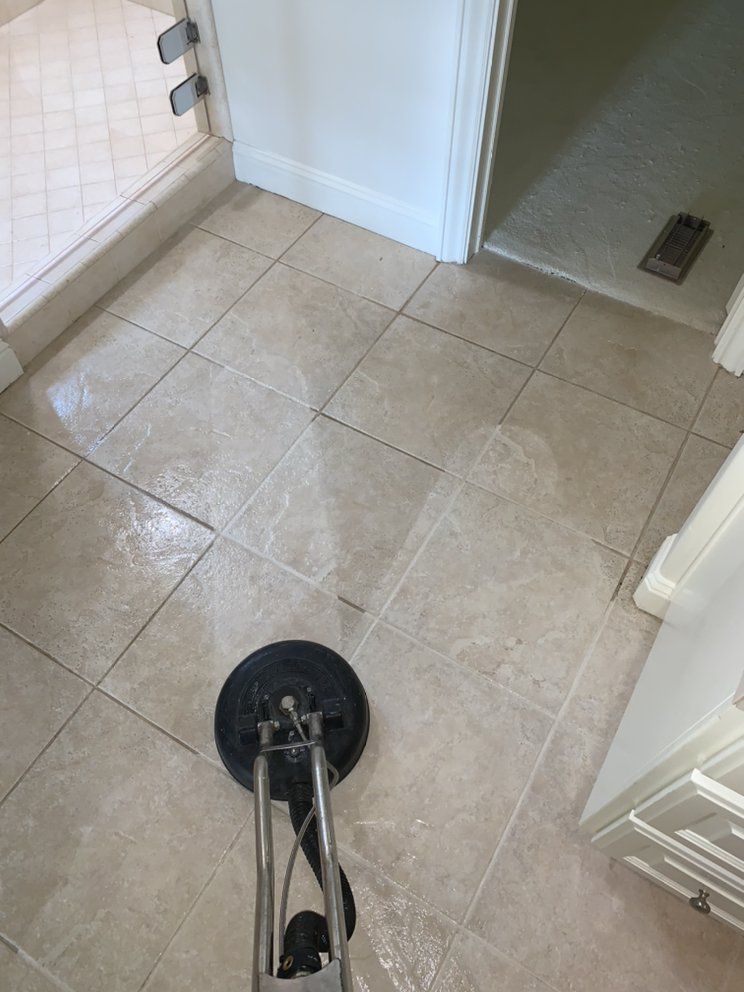 A vacuum cleaner is cleaning a tile floor in a bathroom.