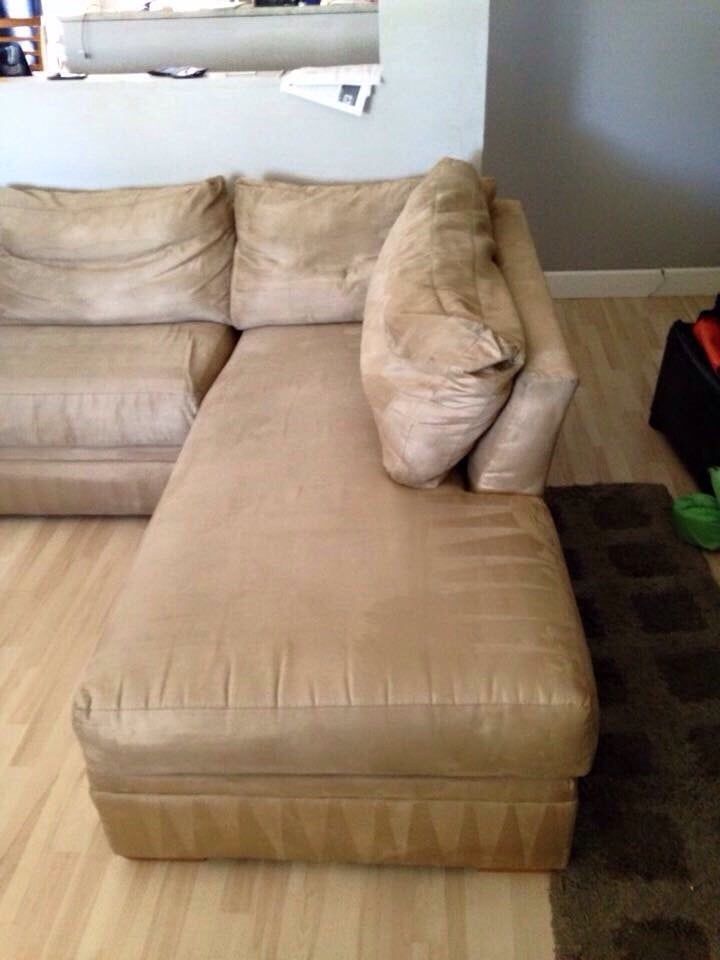 A tan sectional couch is sitting on a wooden floor in a living room.
