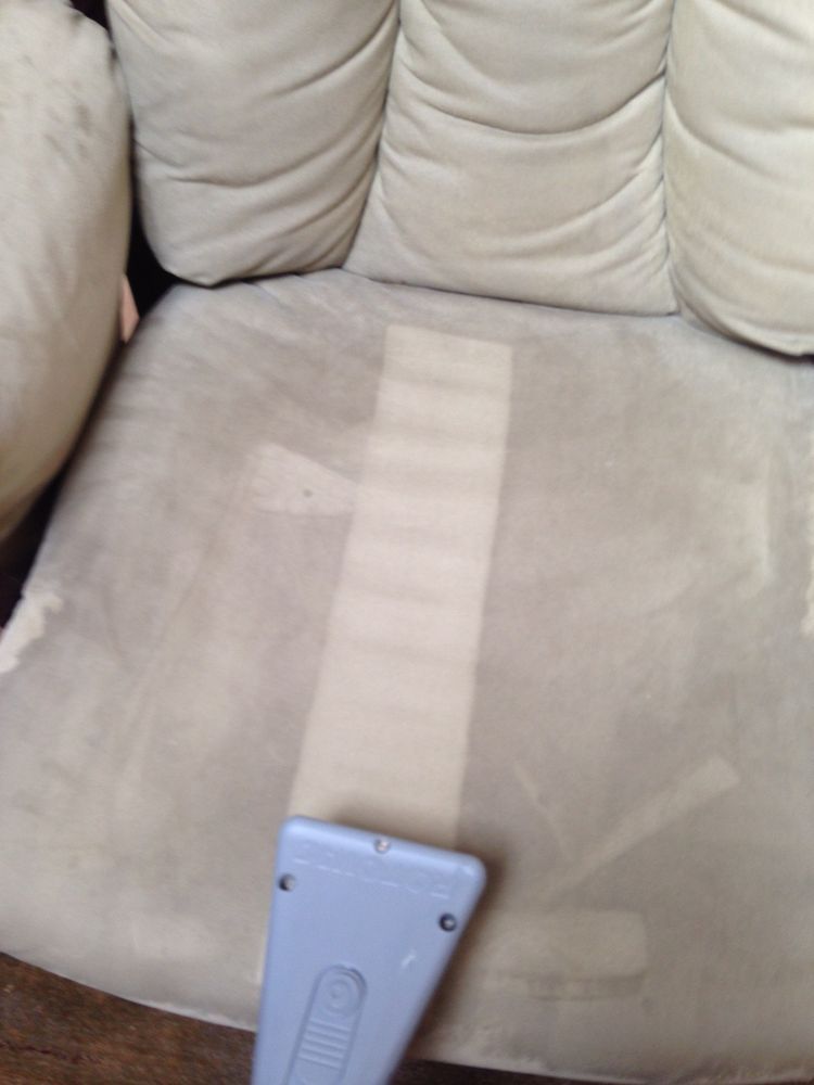 A chair is being cleaned with a vacuum cleaner
