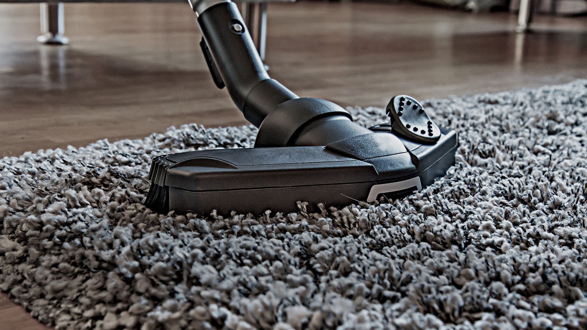 A vacuum cleaner is cleaning a carpet in a living room.