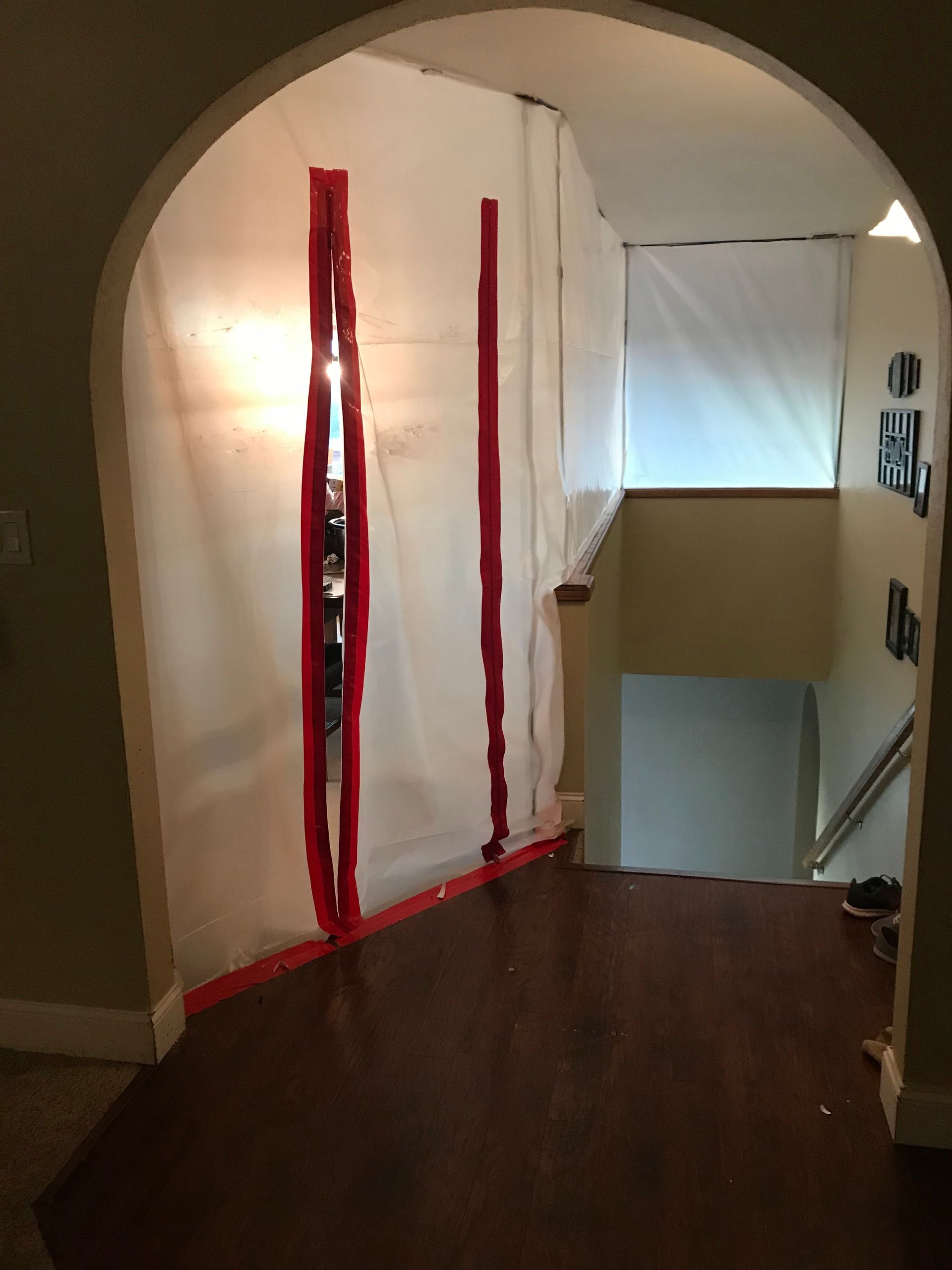 A room with a staircase and a white tarp on the wall