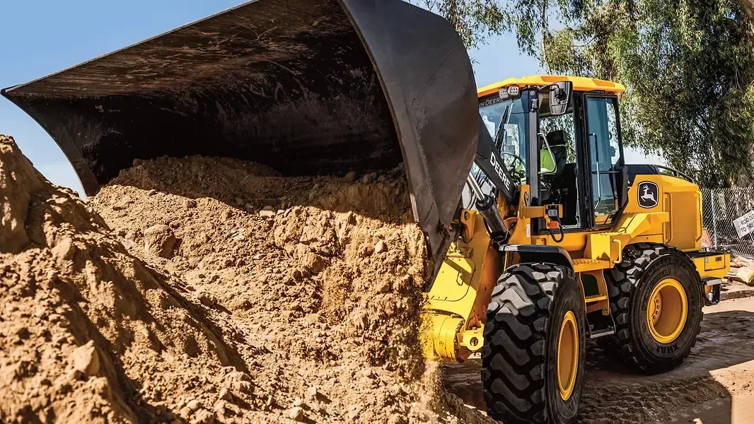 Yellow front loader dumping dirt from a bucket on a construction site