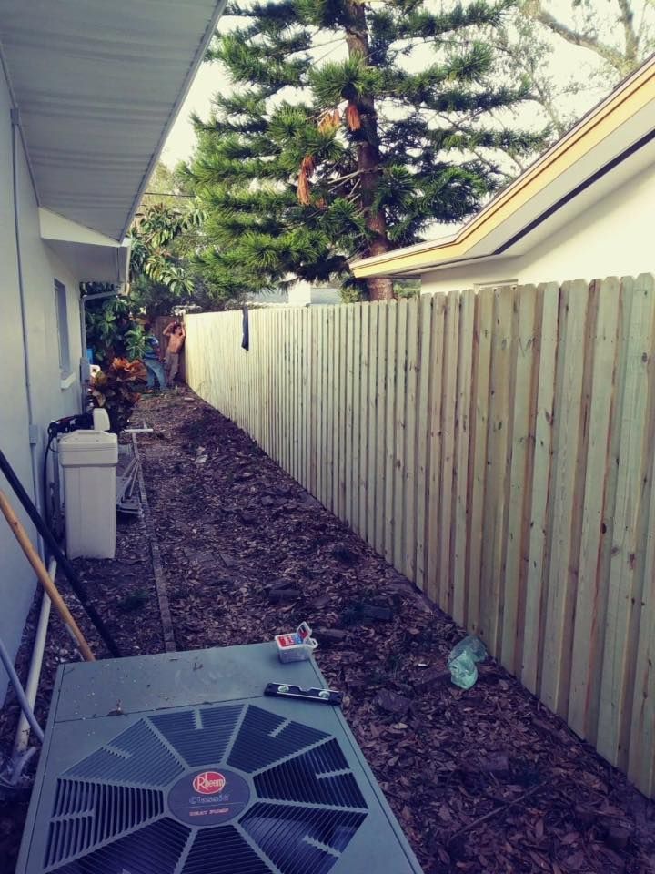 A wooden fence is being built in the backyard of a house.