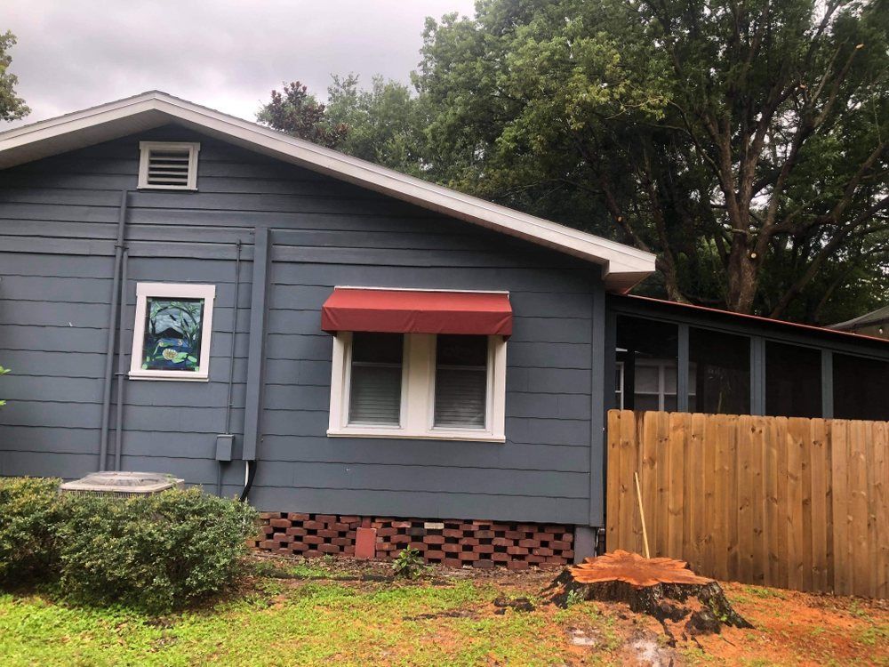 A blue house with a red awning on the window.