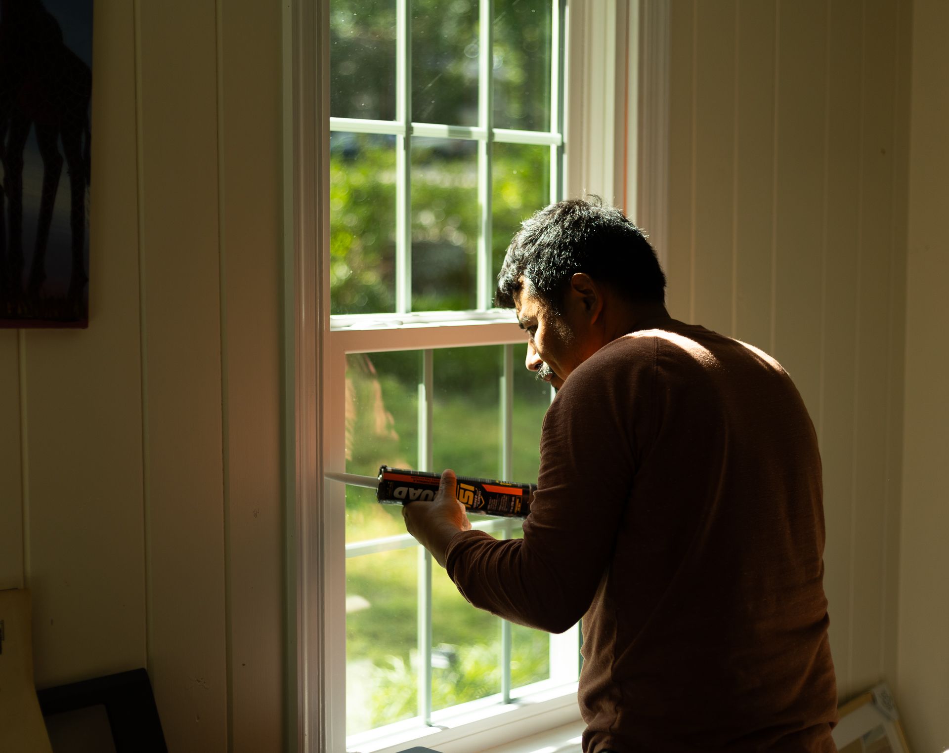 A during-install image of a RETEX window replacement in North Chesterfield VA. This image shows a RETEX crew member caulking.