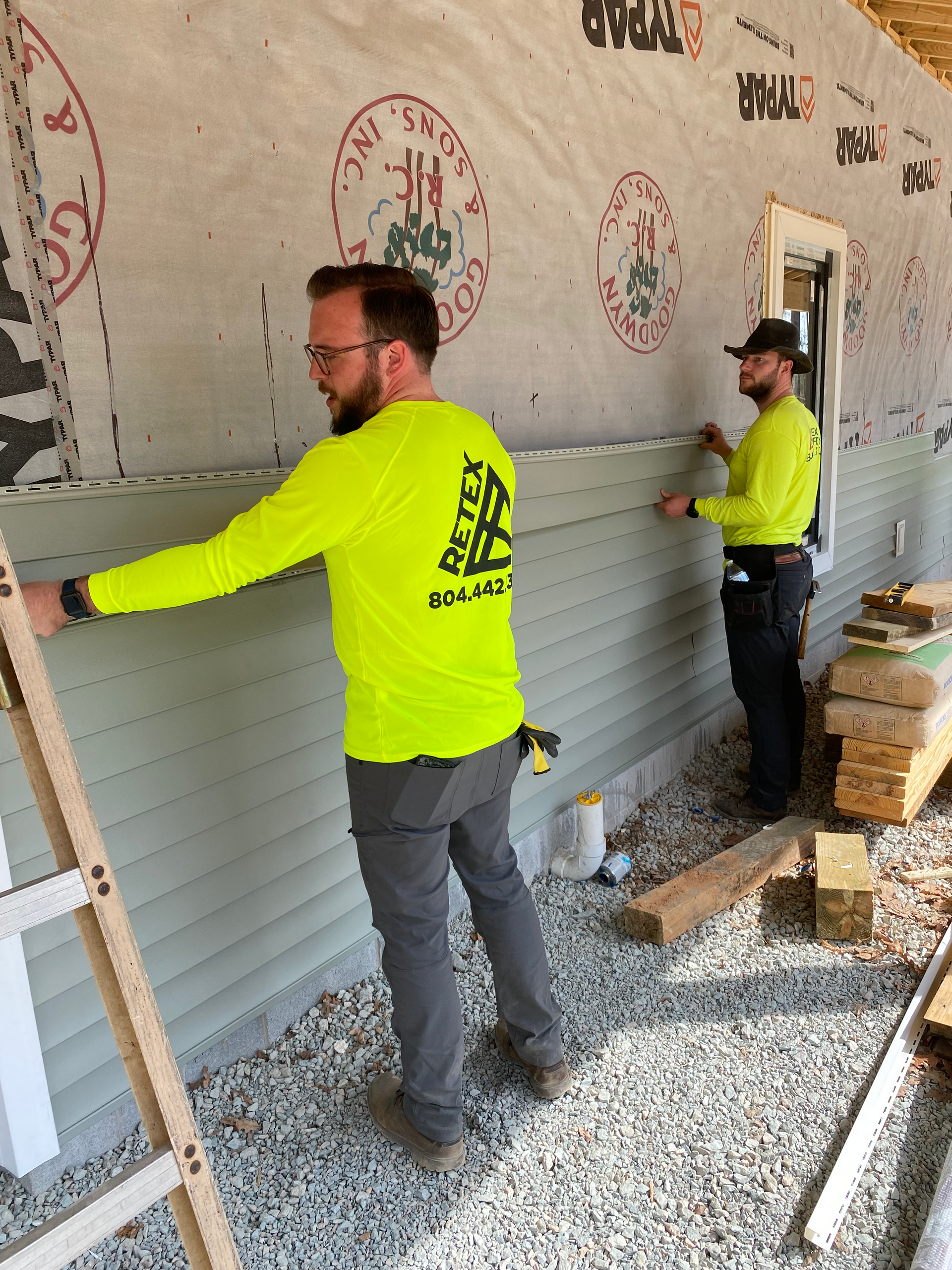 Image of RETEX’s Josh Lewis and Andy Connor volunteering with Meno Life, installing siding.