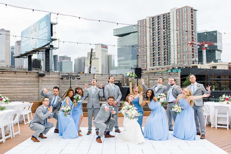 The bride and groom are posing for a picture with their wedding party.